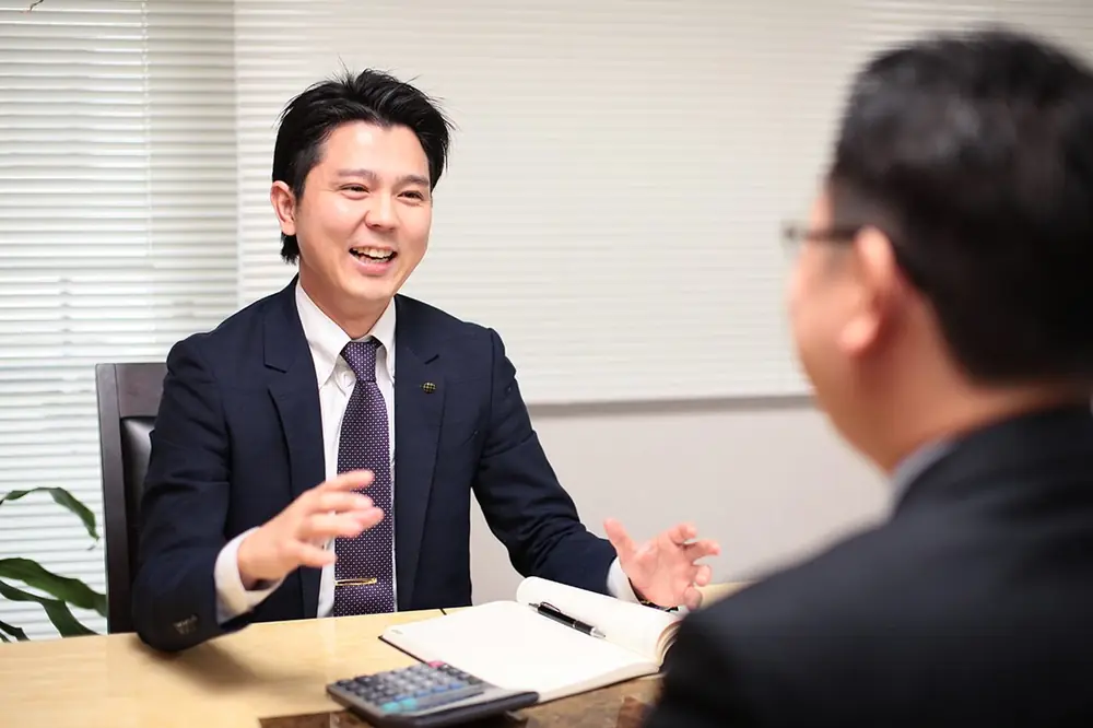 相続・事業承継の相談に机越しで応じる担当者